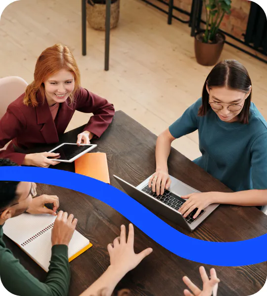 Two colleagues working through a process together at a table with a laptop and notes